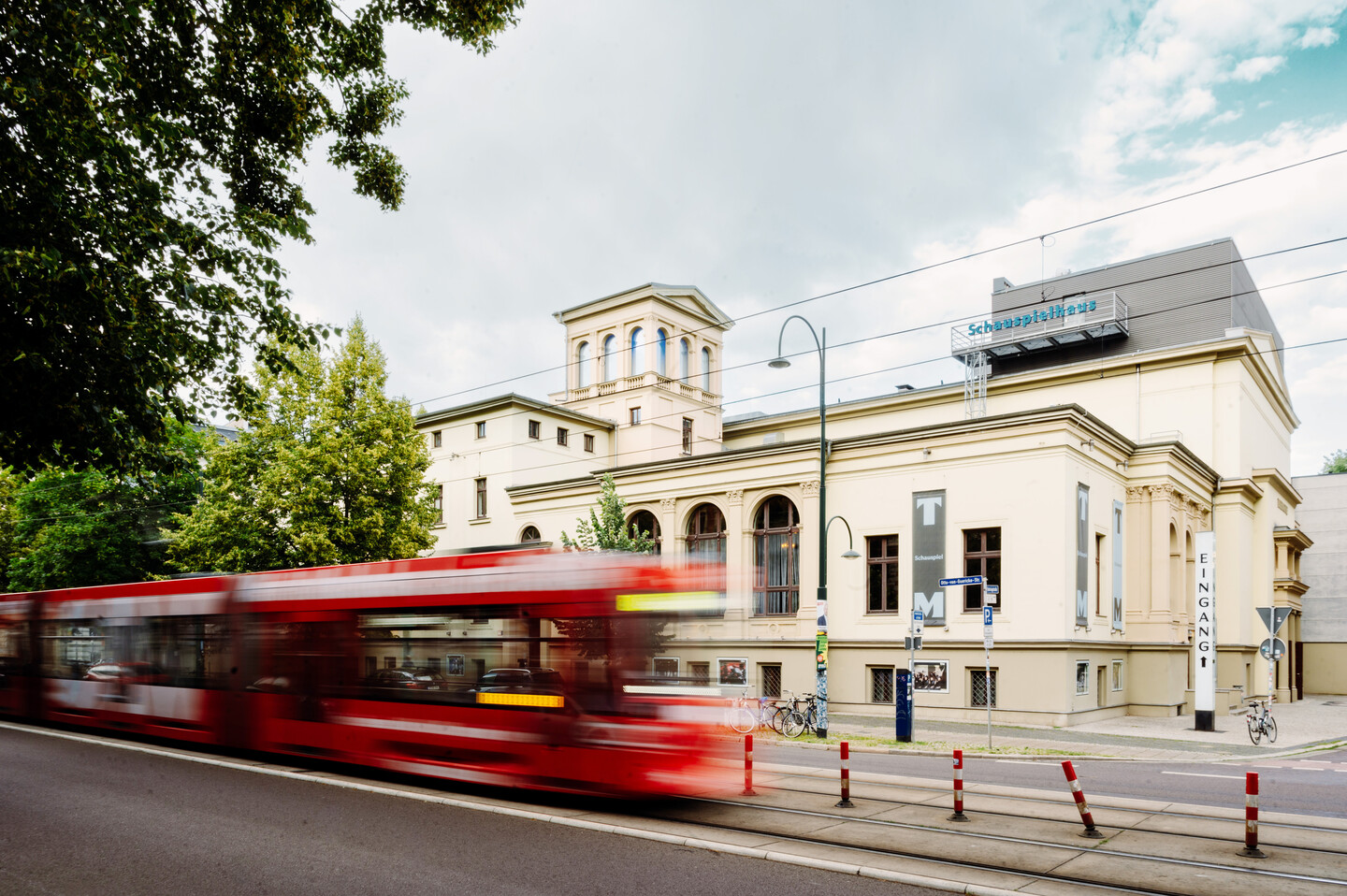 Außenbild des Schauspielhauses. Vor der klassizistische Villa fährt eine rote Straßenbahn vorbei.