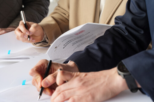 Ein Bildausschnitt von Händen, die die Rahmenvereinbahrung unterschreiben