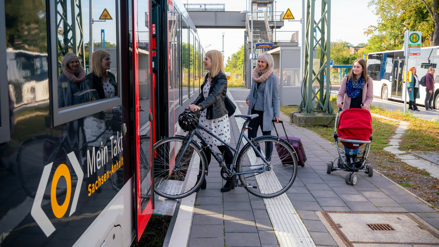 Drei junge Frauen steigen in einen Nahverkehrszug ein. Am Zug ist das Mein-Takt-Zeichen zu sehen.