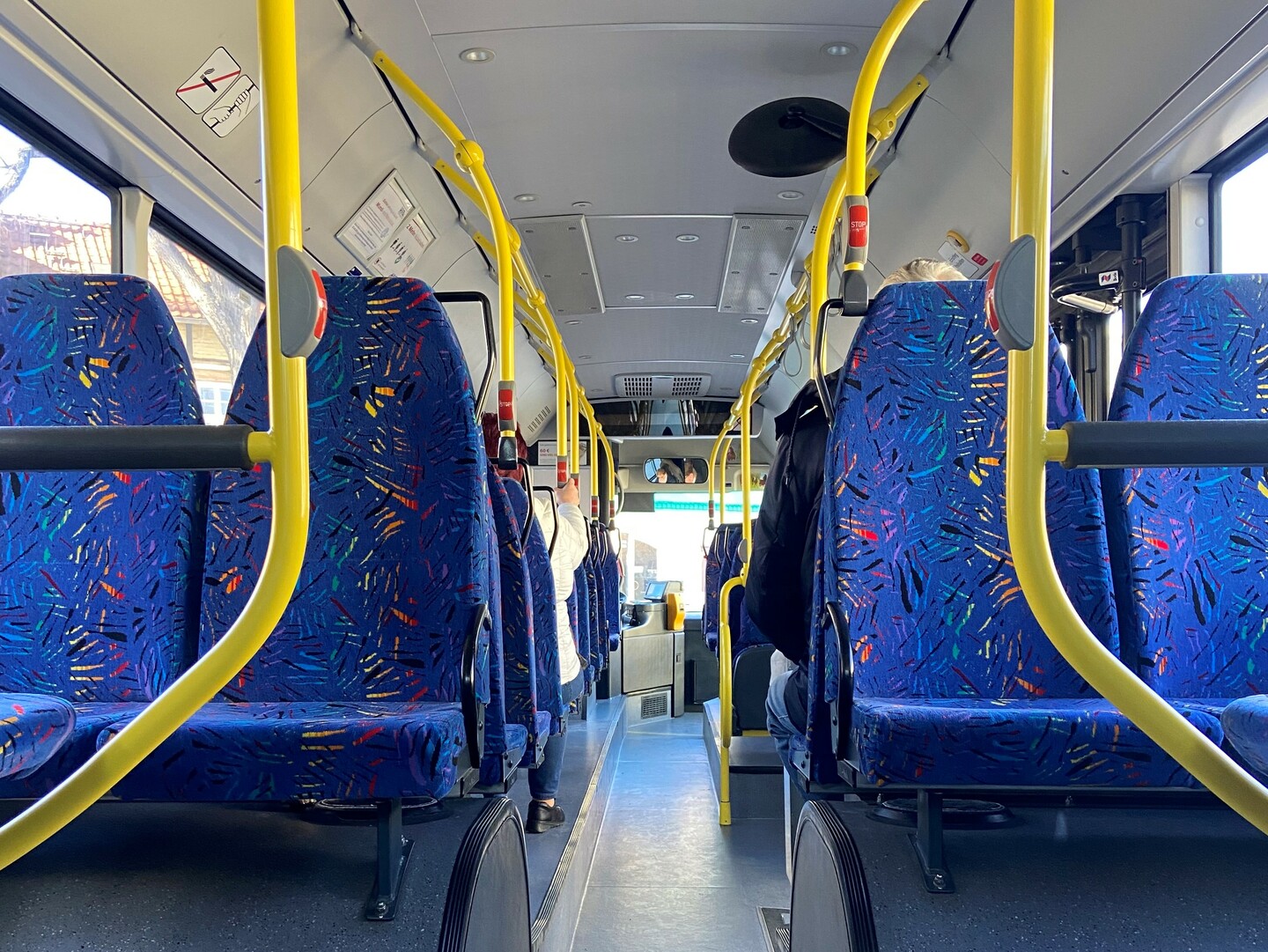 Blick in einen modernen Regionalbus mit blauen Sitzbezügen und gelben Haltestangen.
