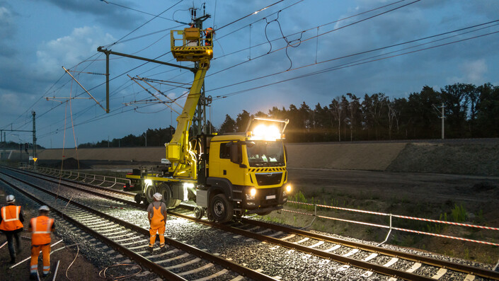 Bauarbeiter arbeiten auf einem Turmwagen an der Oberleitung einer Bahnstrecke (Symbolbild)