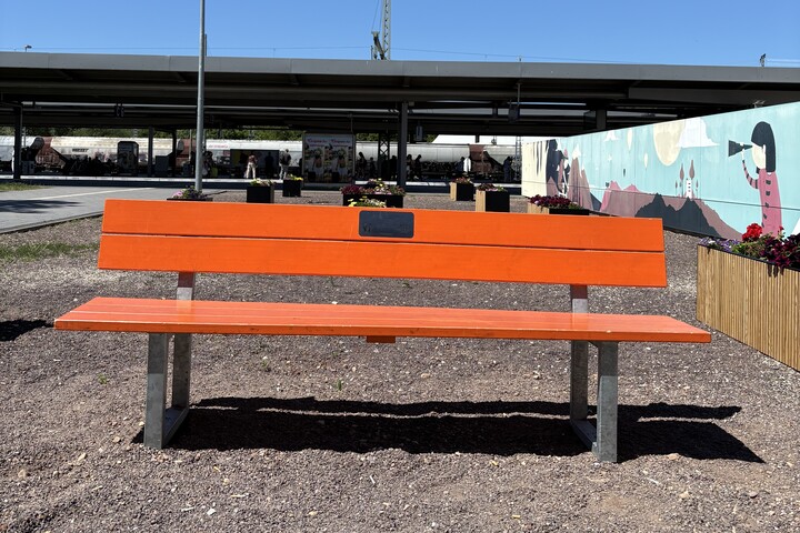 Eine Orange Bank steht auf einem Bahnsteig des Magdeburger Hauptbahnhofs