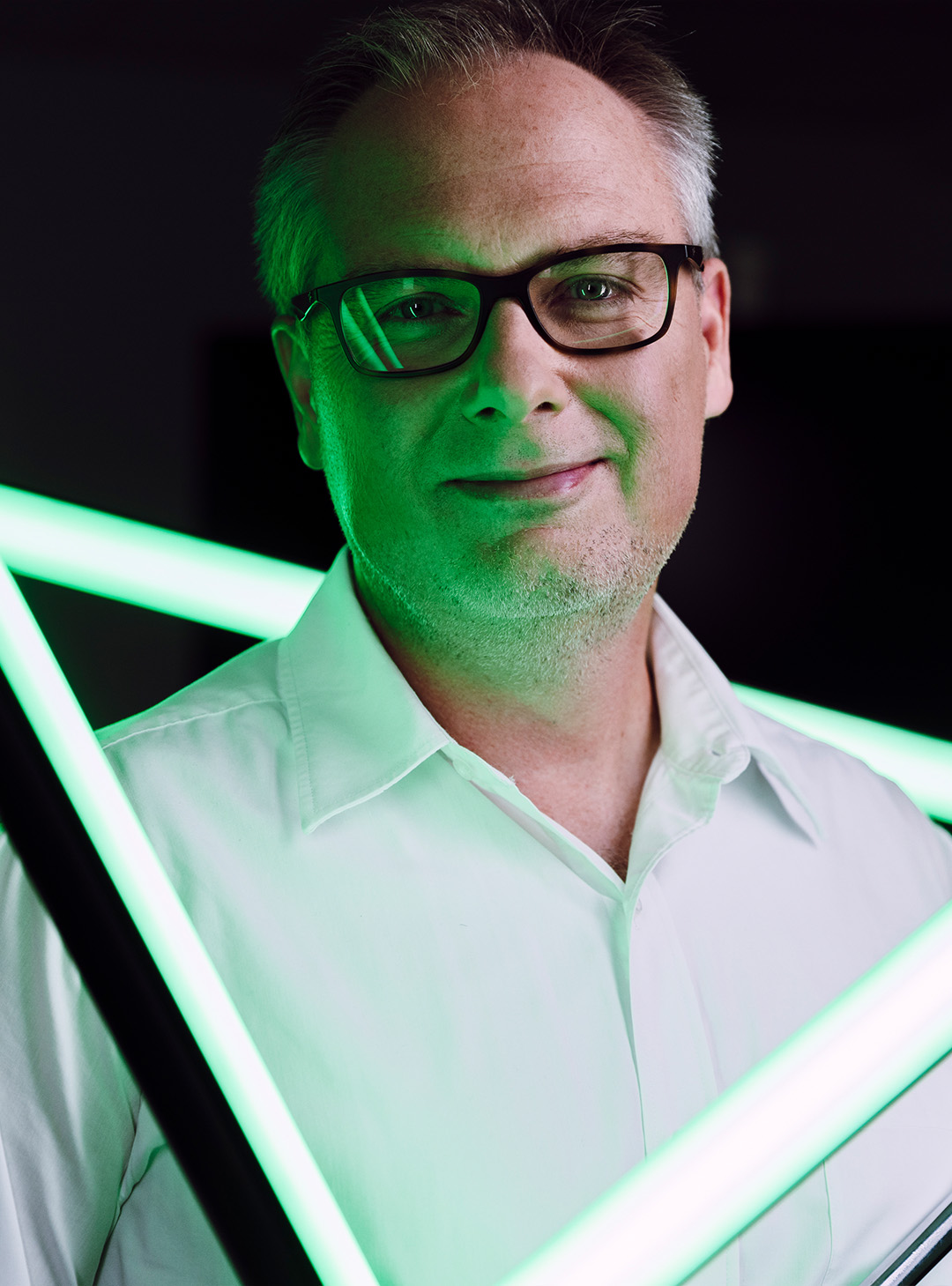 Ein Mann in weißen Hemd wird mit grünem Licht angestrahlt